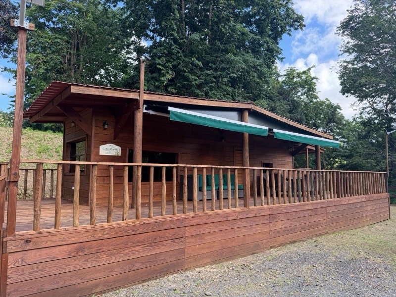 Casa Bambú, a timber cabin with a long wood deck, green awnings and a Casa Bambú sign